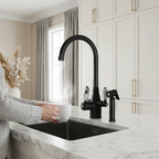 Person holding a white mug under a black kitchen faucet in a modern kitchen.