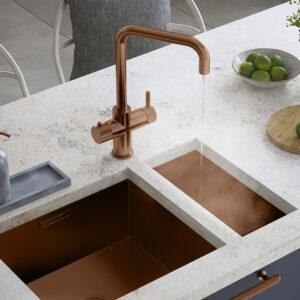 a square-shaped brushed copper boiling water tap on a white kitchen countertop