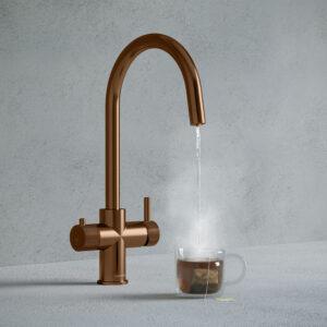a brushed copper swan neck boiling water tap dispensing hot water to a cup of tea