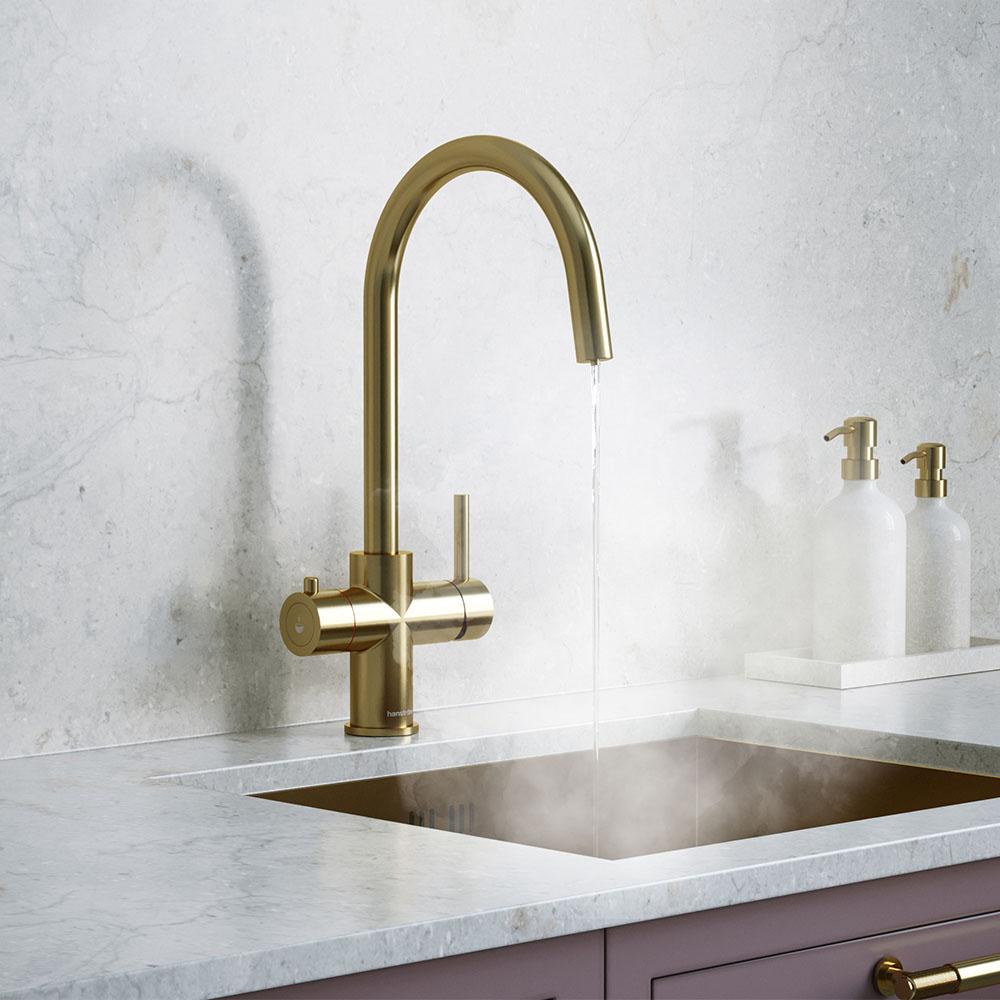  a brushed brass hot water tap beside handwash bottles