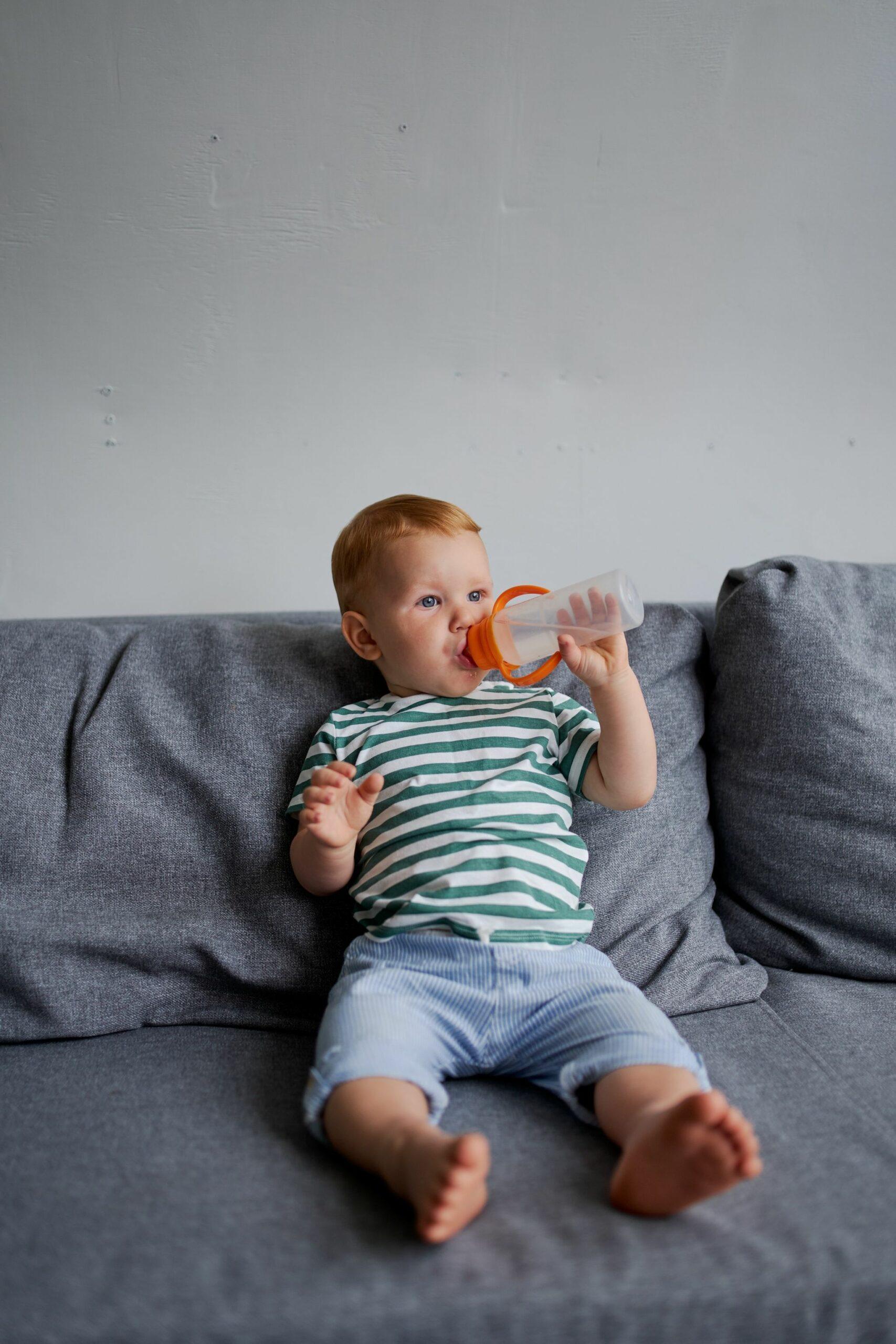 Little boy sitting on a sofa with a bottle
