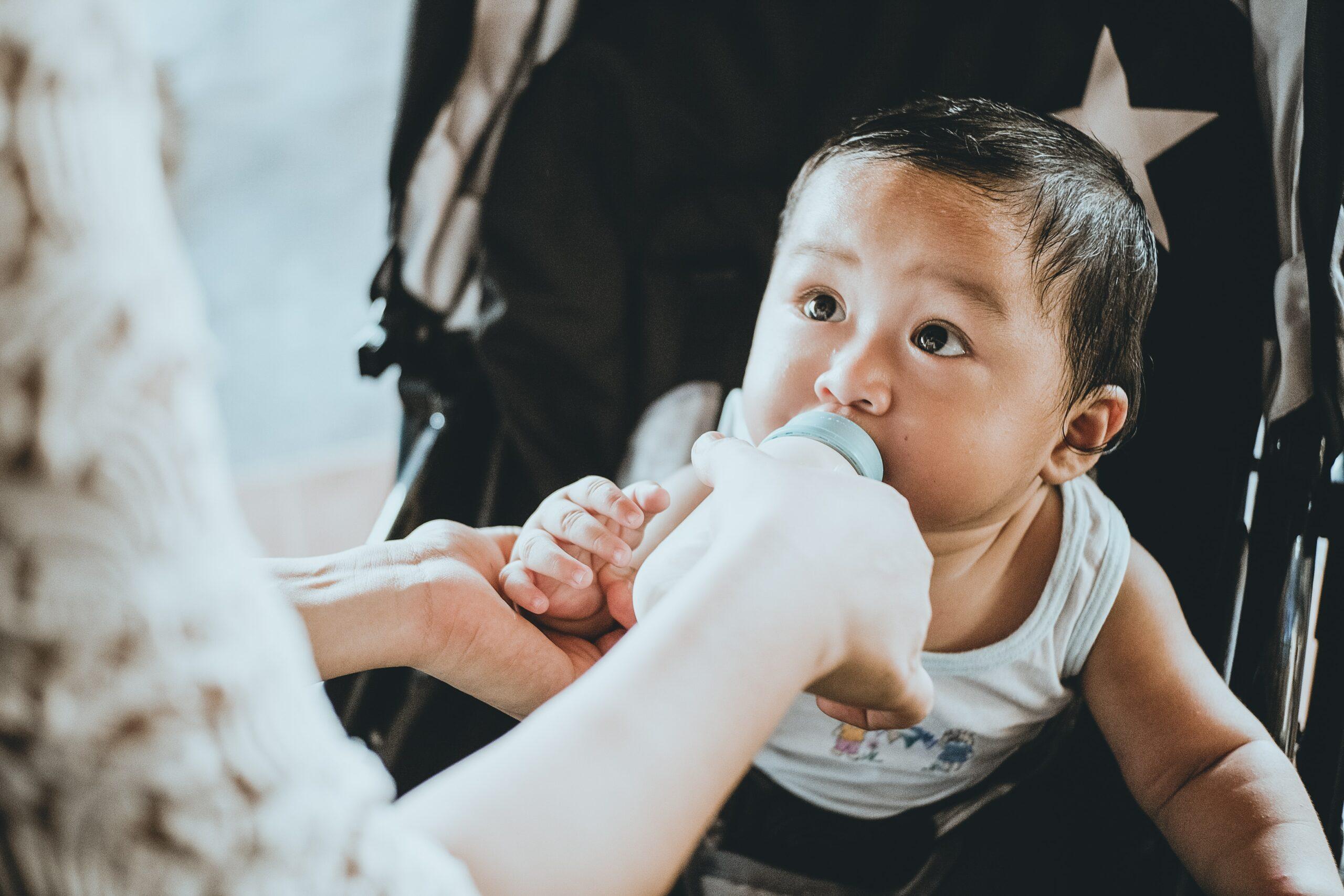 person feeding baby from a bottle