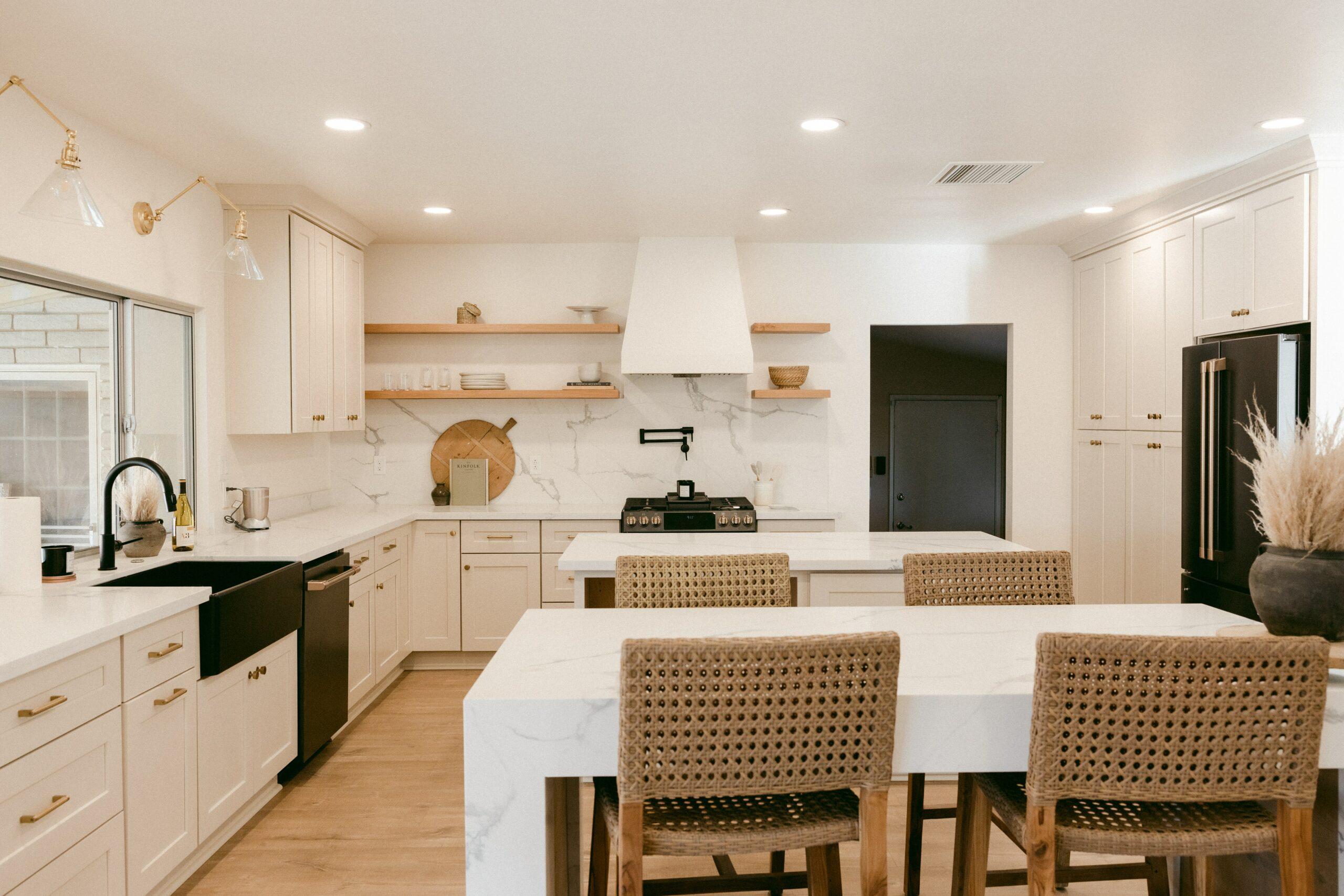 modern kitchen with white backsplashes, two kitchen islands and rattan furniture