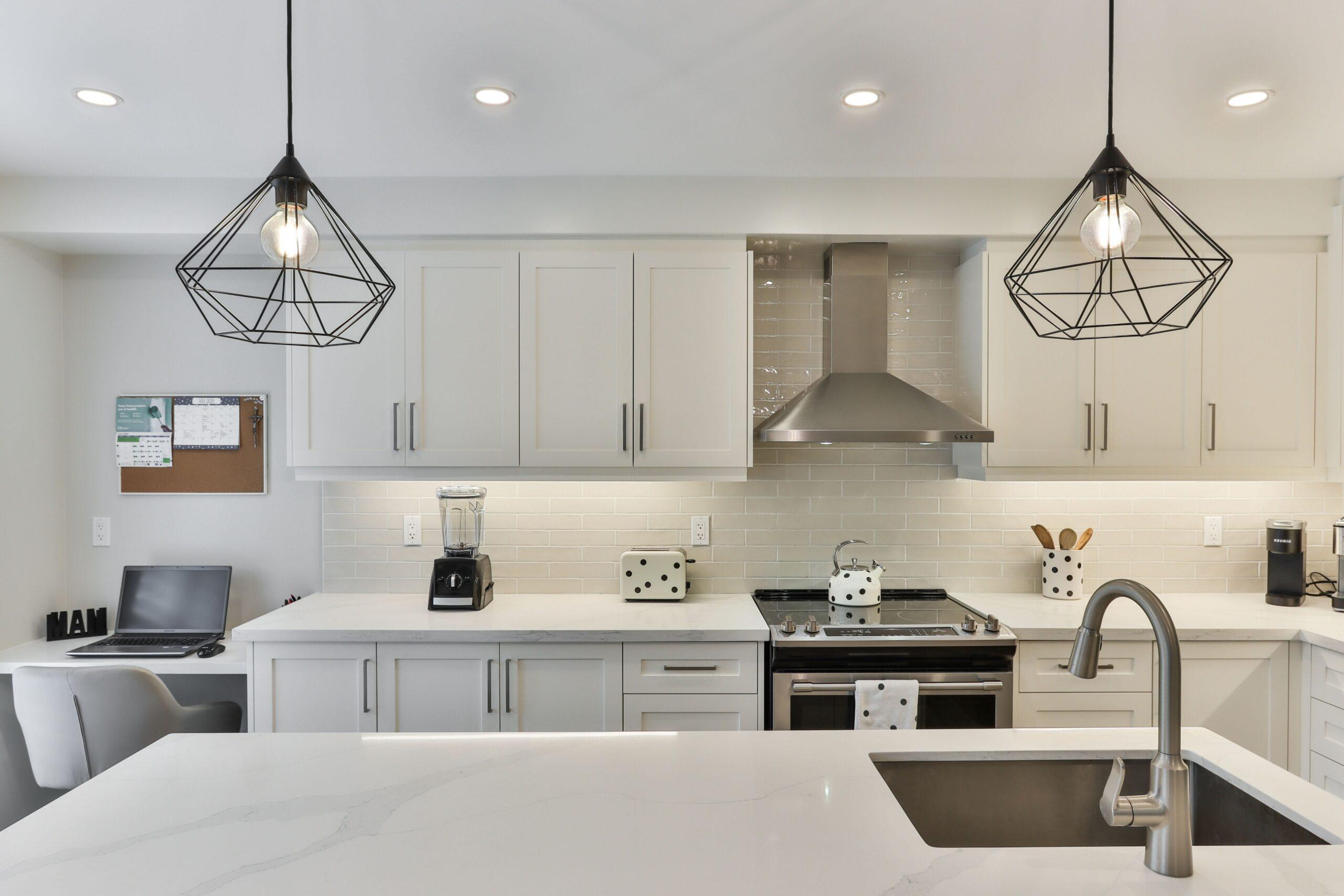 a white wooden kitchen cabinet with black pendant lamp