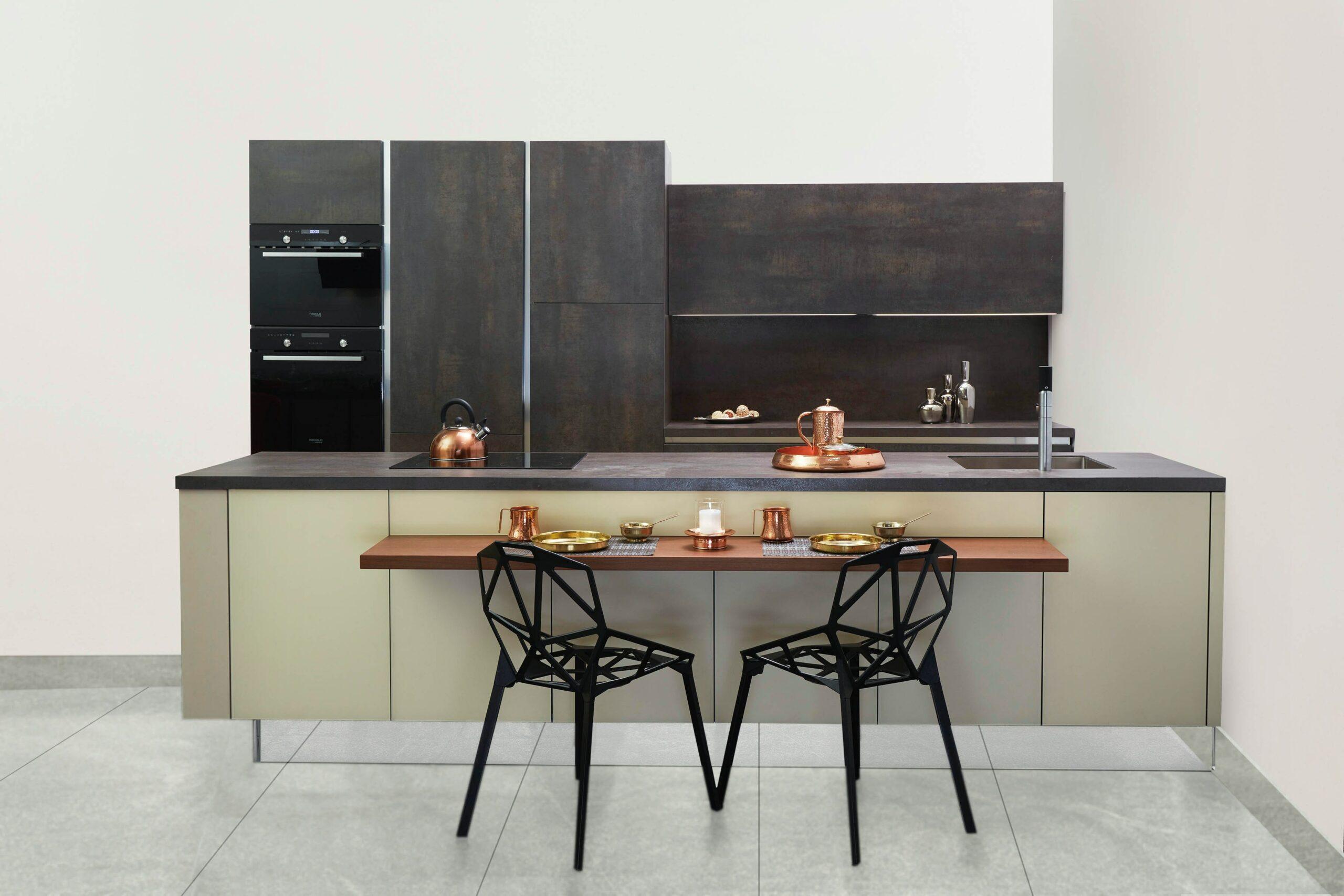 a kitchen interior with two black chairs and rose gold appliances